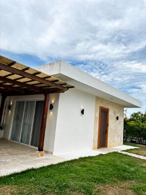 A modern house with a covered patio, a sliding glass door, and a small garden area. - Casa Verde:  Your Tropical Escape in SOV (Sosua)