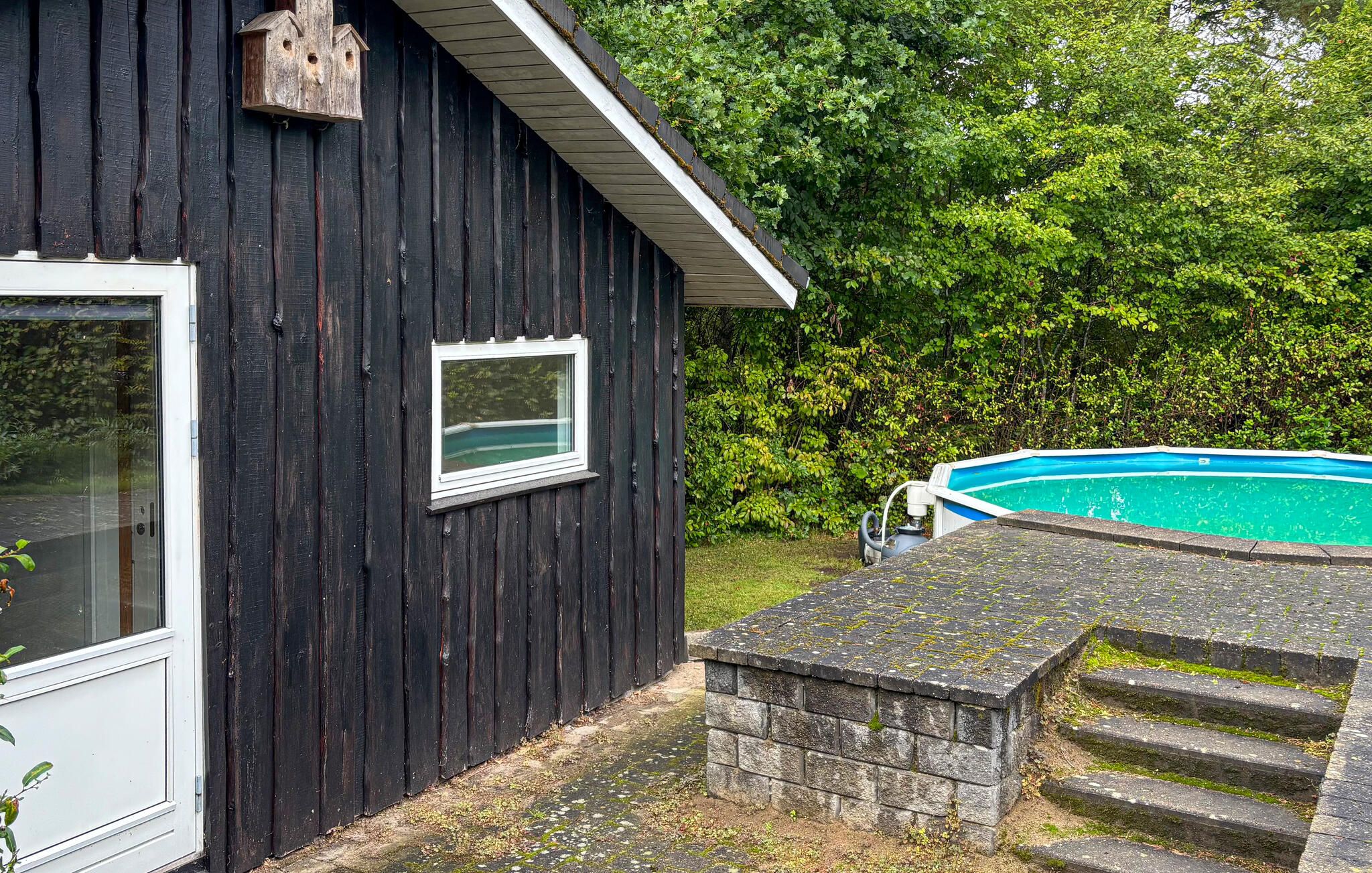A wooden building with a window, a stone staircase, and a swimming pool.