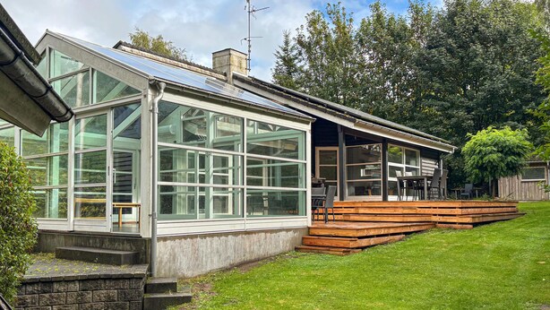 A modern house with large windows, a wooden deck, and a grassy yard. - Cozy home in Kolind with private swimming pool, can be inside or outside (Kolind)