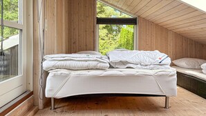 A bed in a room with wooden walls and a sloped ceiling, large windows, and a view of greenery outside. - Cozy home in Kolind with private swimming pool, can be inside or outside (Kolind)