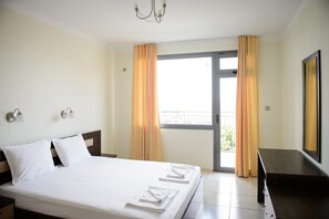 A hotel room with a bed, a TV, a desk, and a balcony with curtains. - Settlement Gardenia Sozopol (Sozopol)