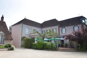 A two-story building with a courtyard, a covered outdoor seating area, and a small garden.