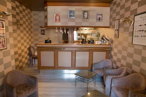 A bar area with a checkered wall pattern, a bar counter, and seating.