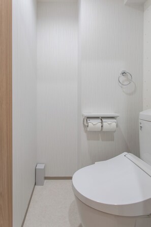 Ein kleines, modernes Badezimmer mit Toilette, Handtuchhalter und Toilettenpapierhalter.