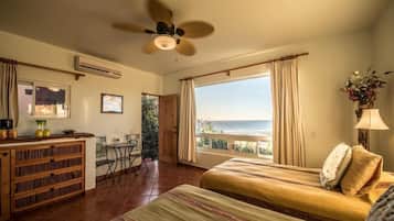 A room with a bed, a desk, and a view of the sea.