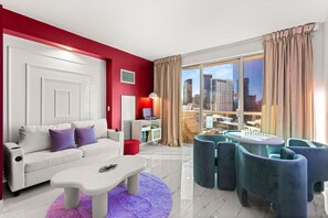 A modern living room with a white sofa, a coffee table, and a city view through large windows. - 777 Suite | Sphere + Strip View | Private Balcony (Las Vegas)