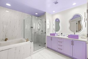 A modern bathroom with a glass-enclosed shower, a white bathtub, and purple vanity cabinets. - 777 Suite | Sphere + Strip View | Private Balcony (Las Vegas)