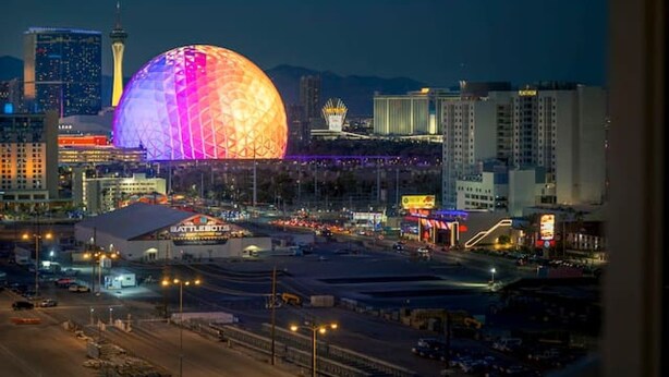 A nighttime cityscape with a prominent dome structure and surrounding buildings. - 777 Suite | Sphere + Strip View | Private Balcony (Las Vegas)