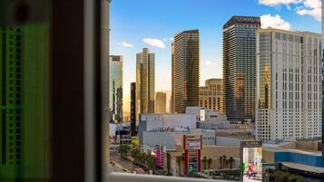 A cityscape with high-rise buildings, including The Cosmopolitan, and a visible street with palm trees and a Planet Hollywood sign.