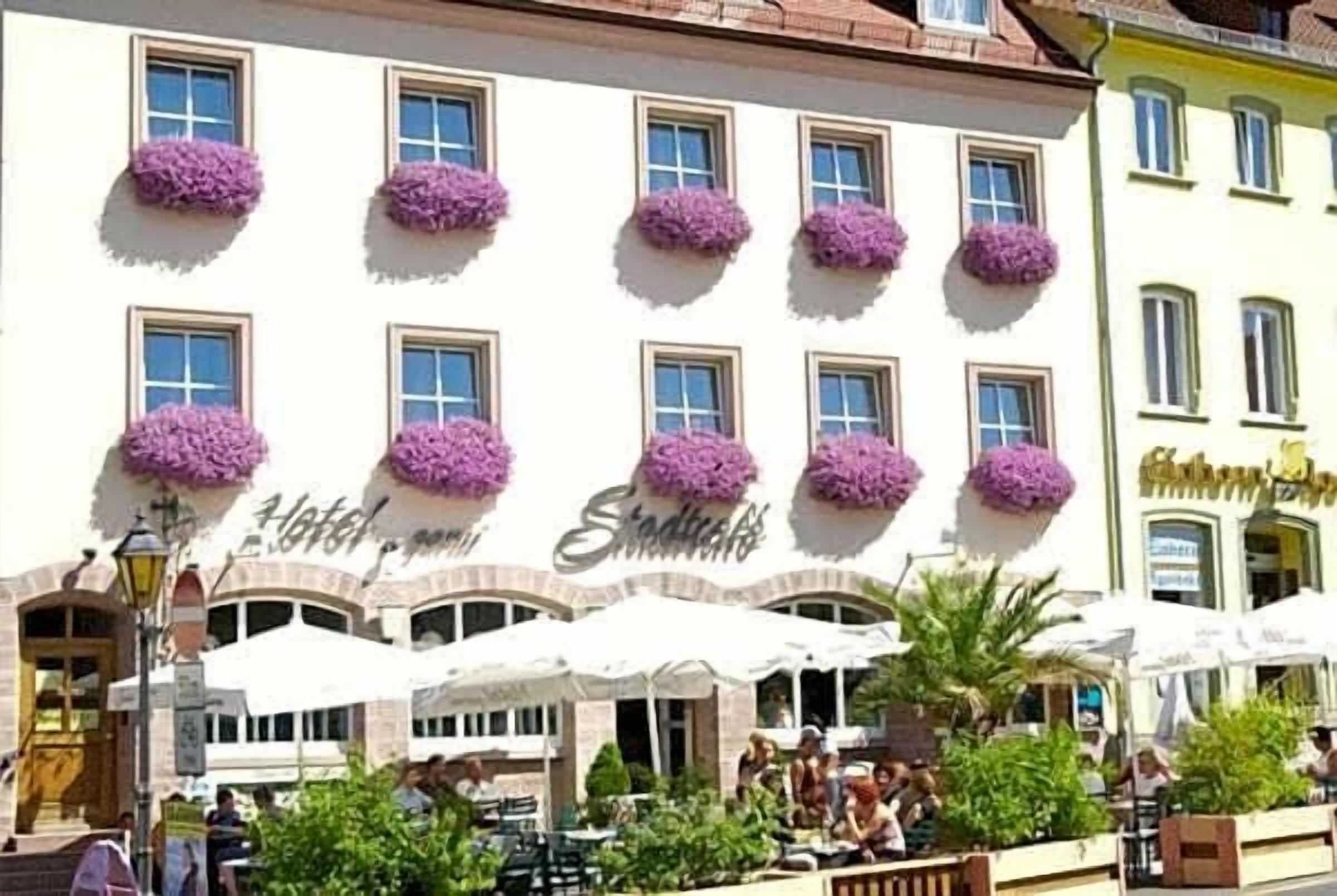 Ein Hotel mit mehreren Fenstern, Außenbereich zum Sitzen und einem Schild, das es als Hotel kennzeichnet.