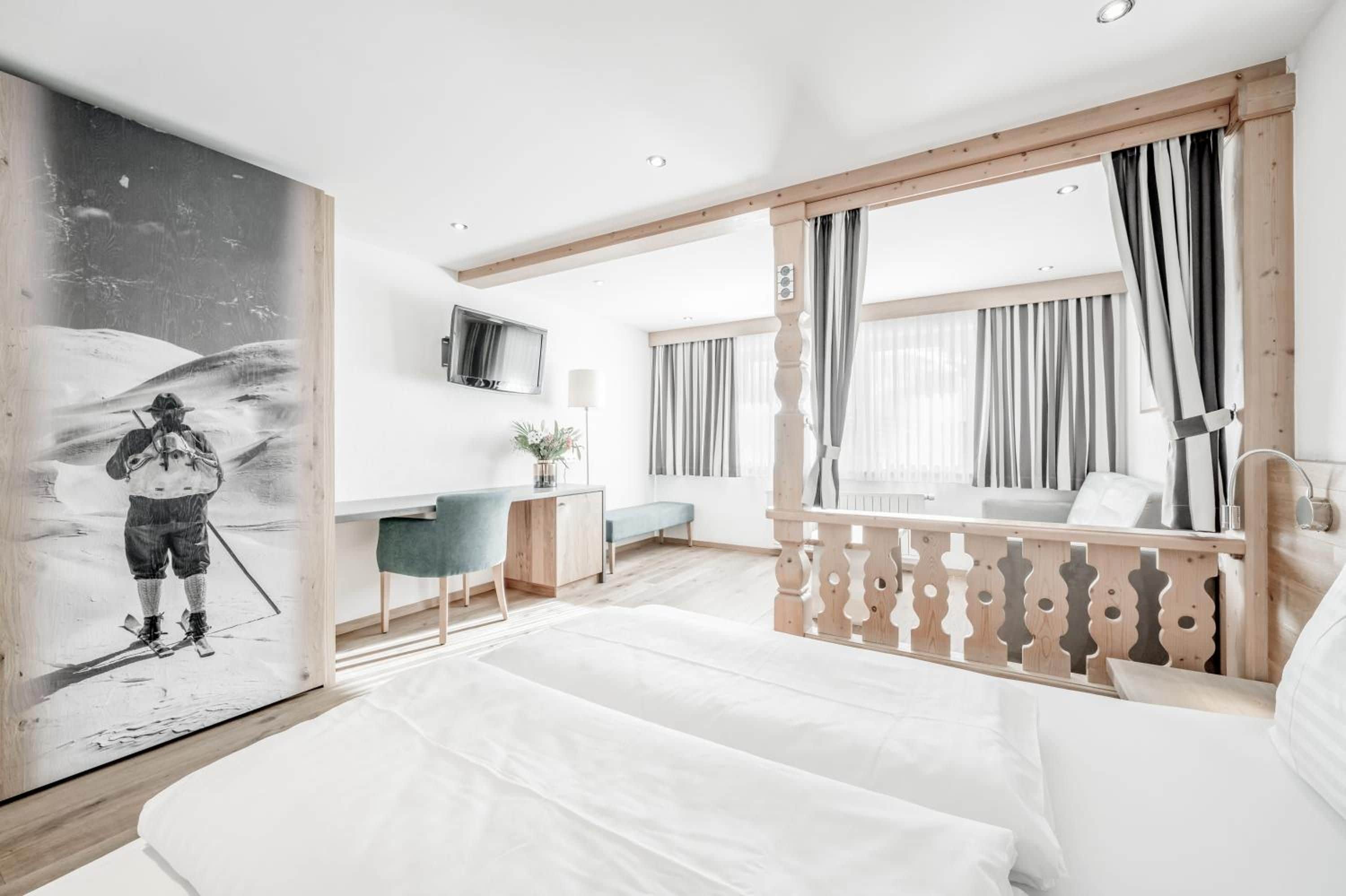 A modern hotel room with a bed, desk, and a large painting.