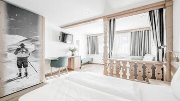 A modern hotel room with a bed, desk, and a large painting.