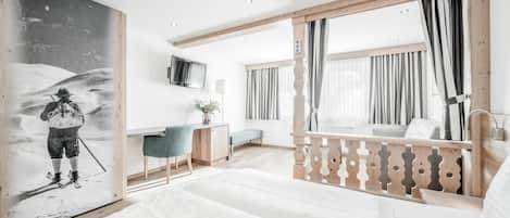A modern hotel room with a bed, desk, and a large painting.