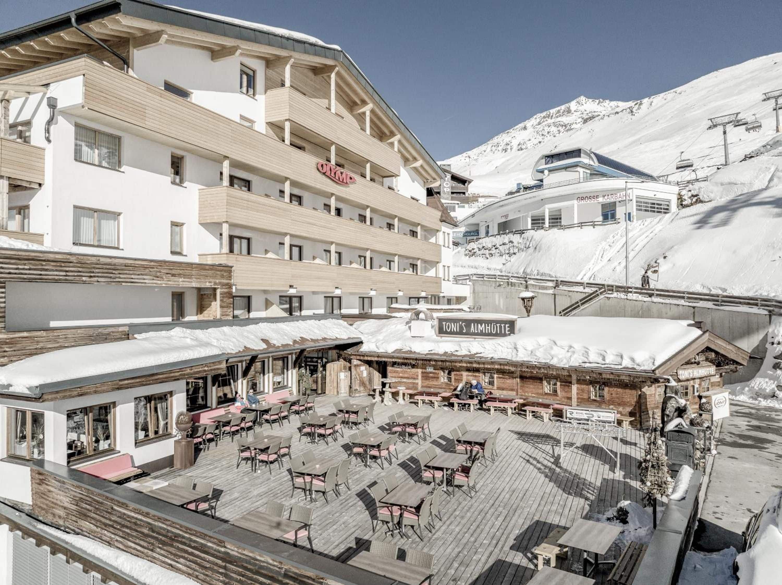 A hotel with outdoor seating and a sign reading 'TONI'S ALMHÖTTE'.