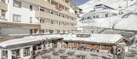 A hotel with outdoor seating and a sign reading 'TONI'S ALMHÖTTE'.