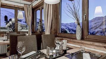 A restaurant with a wooden interior, large windows with mountain views, and a table set for dining.