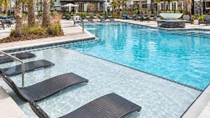 Una piscina con agua cristalina, rodeada de sillas de descanso y palmeras.