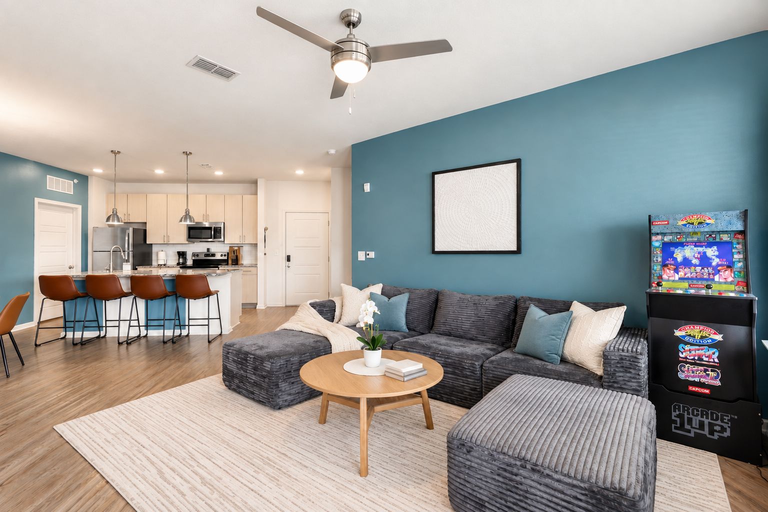 A modern living room with a sofa, ottoman, coffee table, and a gaming console.