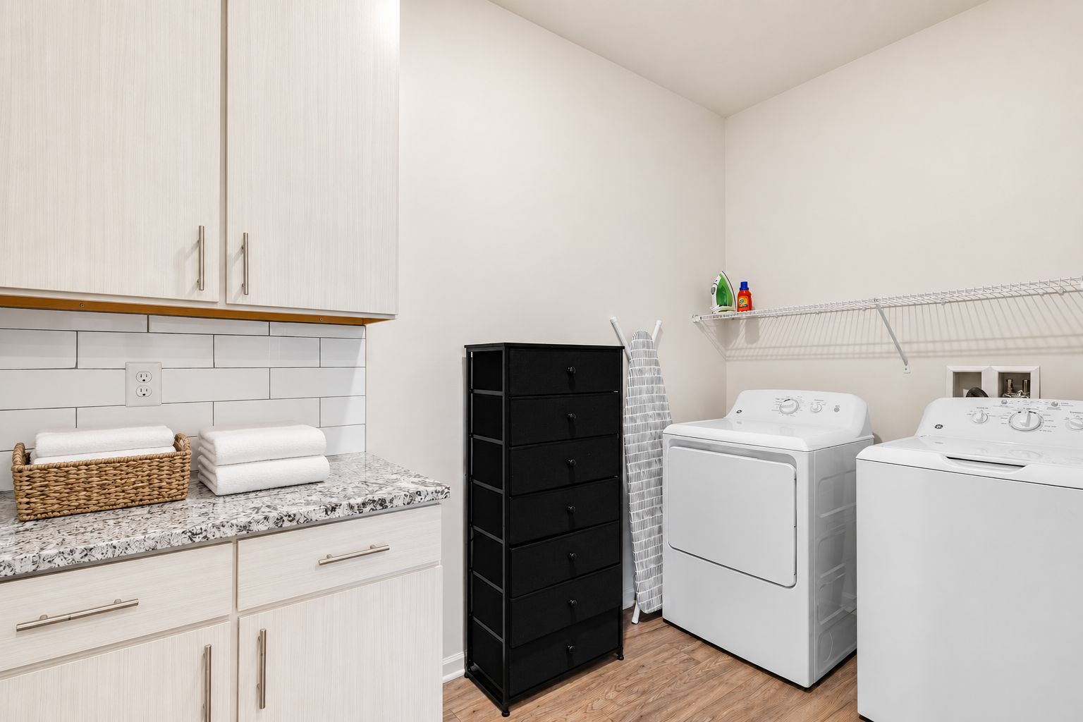 A laundry area with a washing machine, dryer, and stacked black drawers.