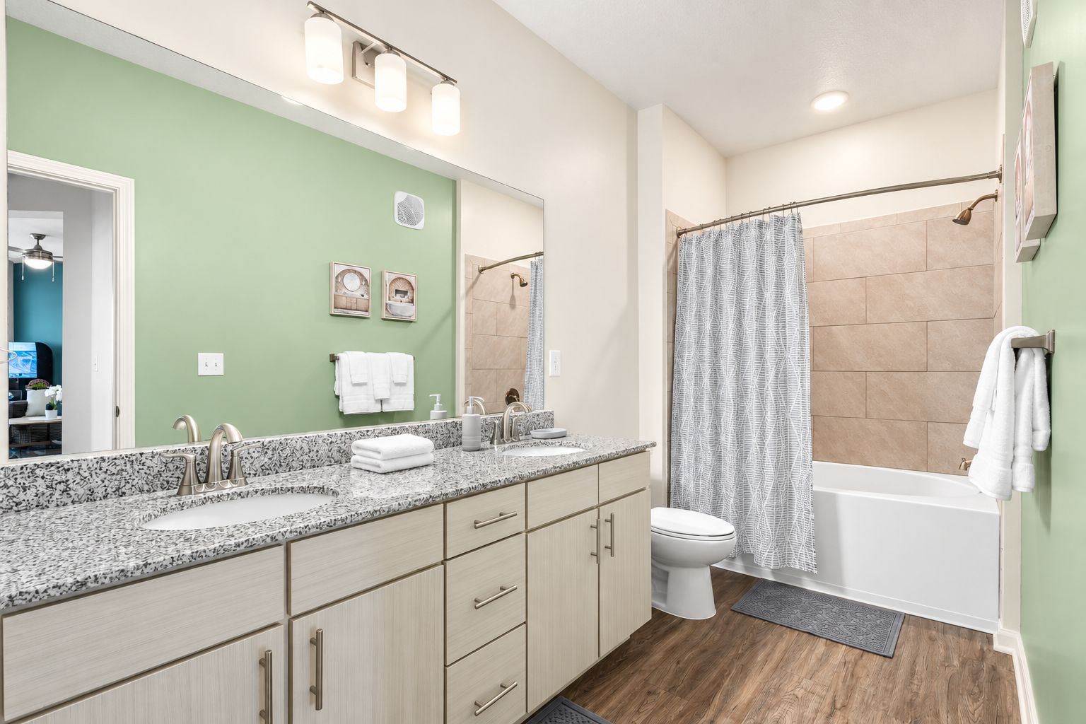 Une salle de bain avec un meuble-lavabo à deux vasques, des toilettes, une douche avec une porte en verre et un porte-serviettes.
