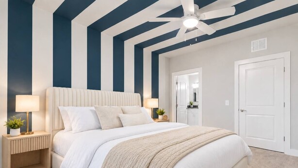 Un dormitorio con una cama grande, mesitas de noche, ventilador de techo y una puerta que da a otra habitación.