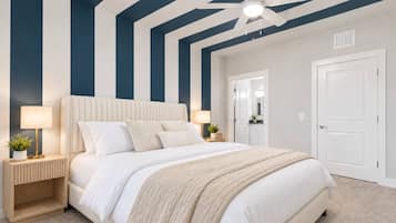 A bedroom with a large bed, bedside tables, a ceiling fan, and a door leading to another room.