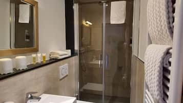 Ein modernes Badezimmer mit einer gläsernen Duschkabine, einem weißen Waschbecken und einem Handtuchhalter.