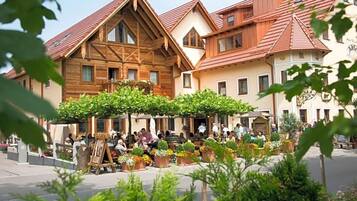 Ein traditionelles europäisches Gebäude mit einer Holzfassade, einem Balkon und einem Innenhof mit Blumentöpfen und Sitzgelegenheiten.