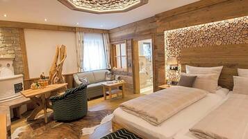 Ein gemütliches Schlafzimmer mit einem großen Bett, einem Holz-Kopfteil, einem kleinen Tisch, einer Couch und einer dekorativen Wand.