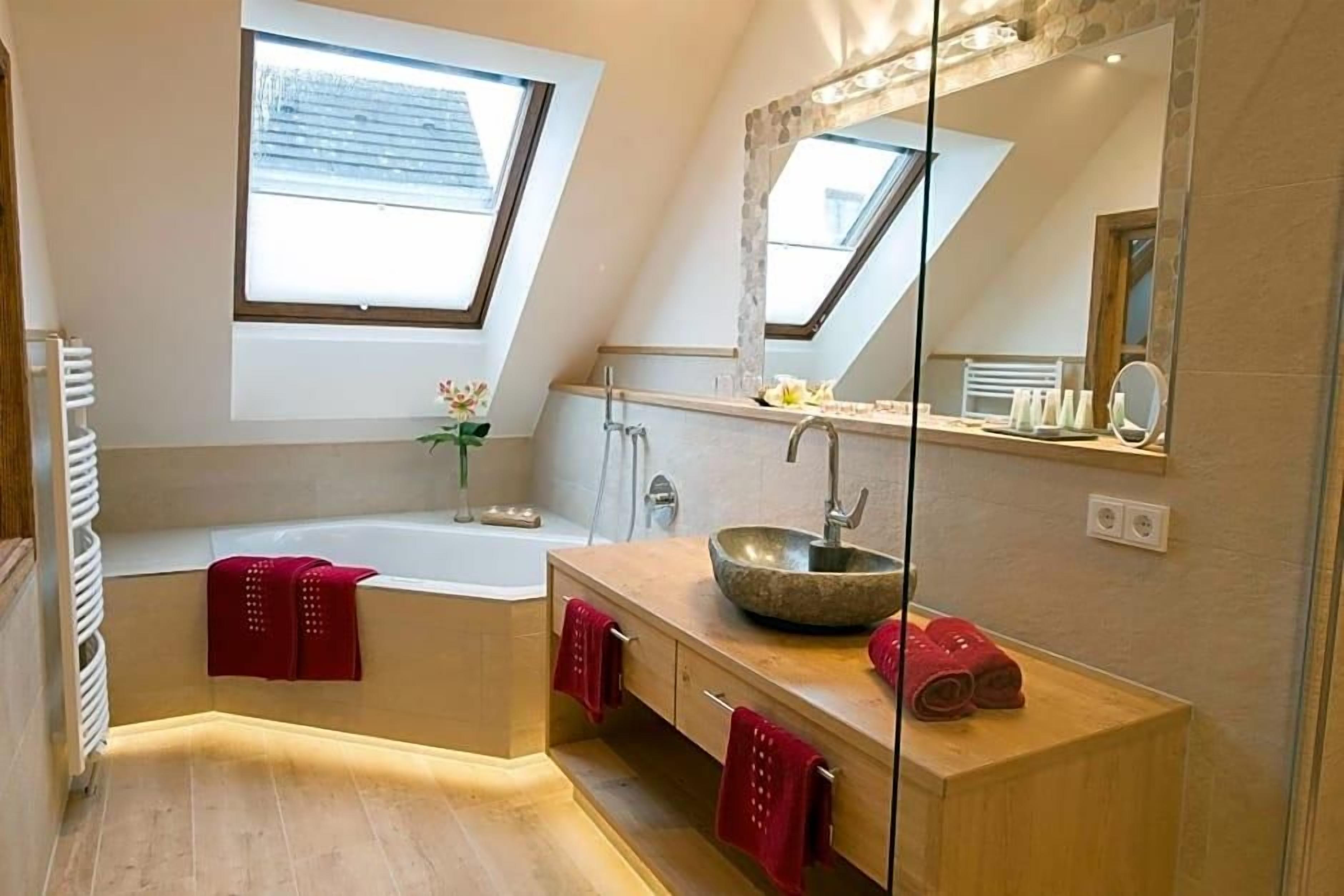 Ein modernes Badezimmer mit Dachfenster, einer freistehenden Badewanne, einem großen Spiegel und einem Holzbadezimmer-Möbel.