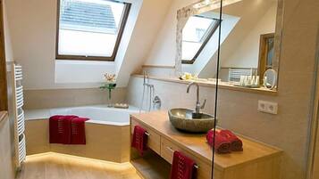 Ein modernes Badezimmer mit Dachfenster, einer freistehenden Badewanne, einem großen Spiegel und einem Holzbadezimmer-Möbel.