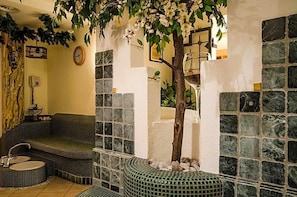 Un espacio de spa con un banco de azulejos, un lavamanos pequeño y un árbol.