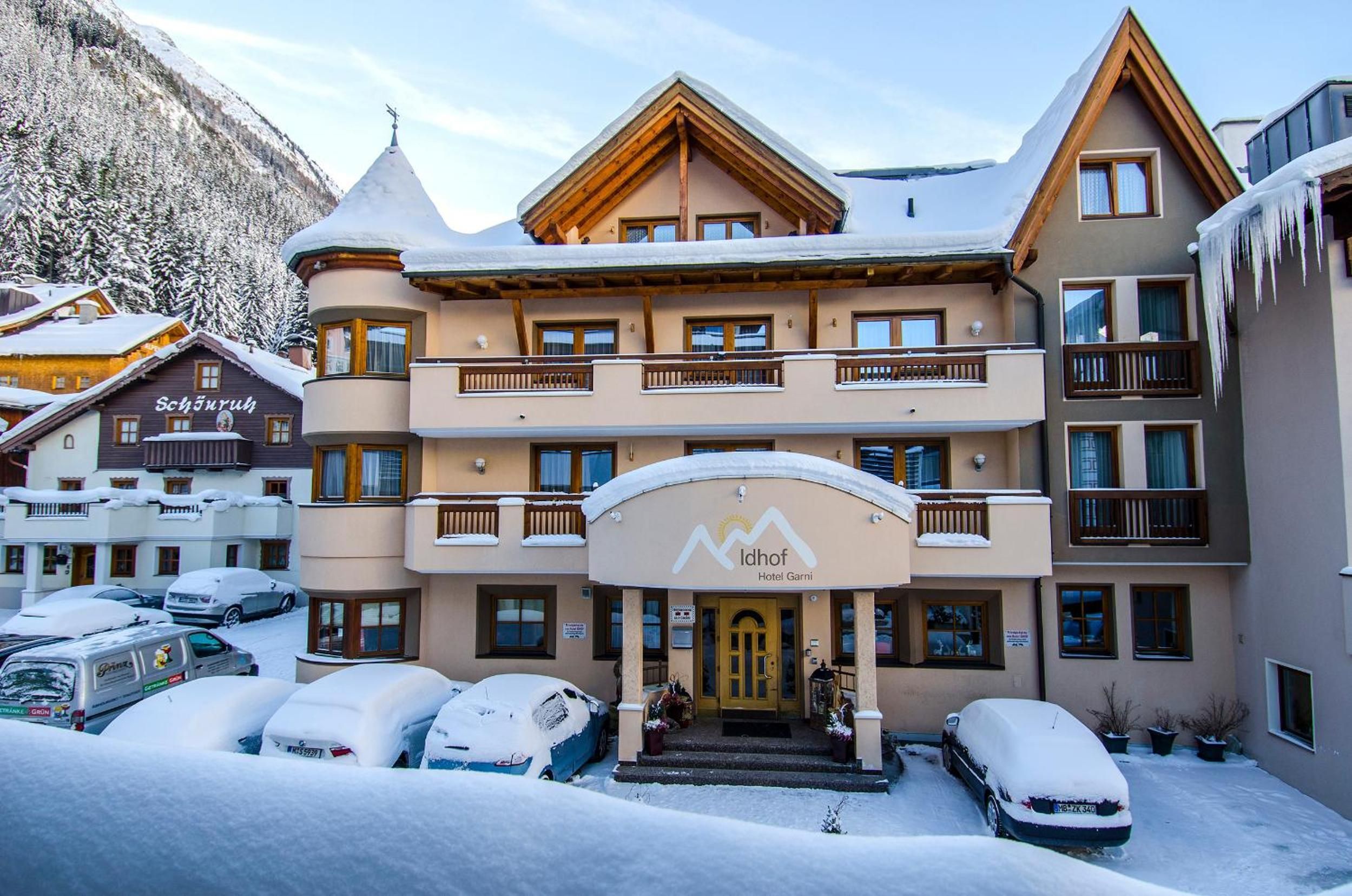 Un hôtel à l’architecture imposante, avec de nombreux étages, des balcons et une entrée recouverte de neige.