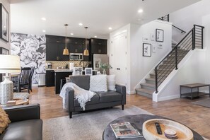 A modern living room with a sofa, coffee table, and a staircase leading to an upper level. - Pet Friendly! New beautifully decorated! Hot tub, Arcade Minutes from Deer Valley and Main Street (Hideout)