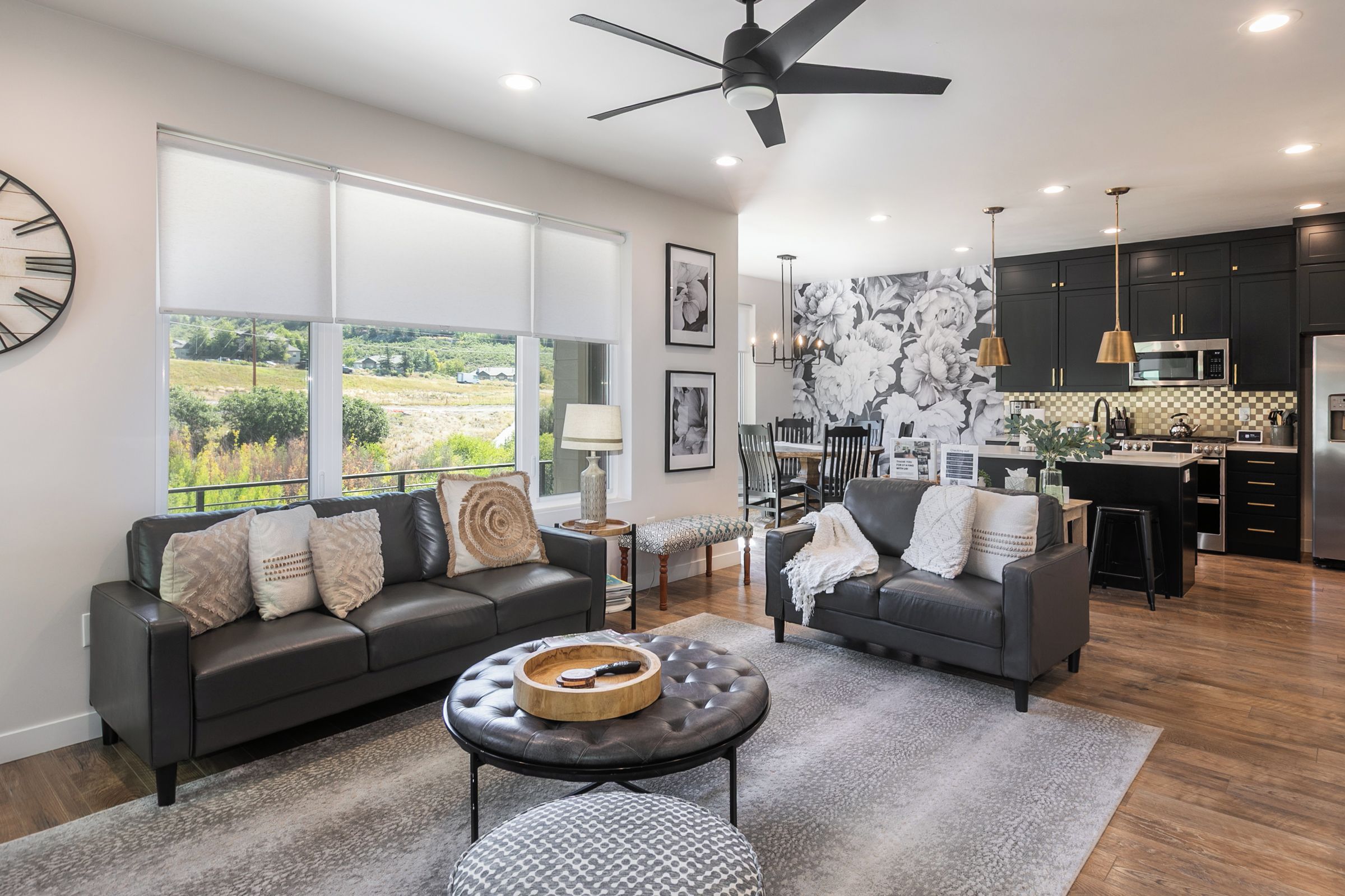 A modern living room with a sofa, ottoman, and a dining area with chairs and a table.
