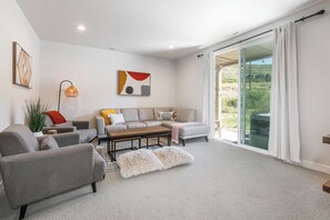 A modern living room with a sofa, armchairs, a coffee table, and a large window with a view of the outdoors. - Pet Friendly! New beautifully decorated! Hot tub, Arcade Minutes from Deer Valley and Main Street (Hideout)