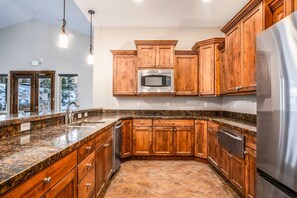 A kitchen with wooden cabinets, a stainless steel refrigerator, and a granite countertop. - Minutes to Deer Valley & Old Town! Private Hot Tub! Beautiful New Home! (Hideout)