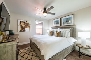 A bedroom with a bed, a desk, a chair, a lamp, a ceiling fan, and two framed pictures on the wall. - Minutes to Deer Valley & Old Town! Private Hot Tub! Beautiful New Home! (Hideout)