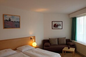 A hotel room with a bed, a sofa, a small table, and two framed pictures on the walls. - Hotel Deisterblick (Bad Nenndorf)
