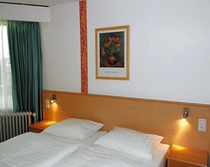 A hotel room with a double bed, two bedside tables, a nightstand, a framed picture on the wall, and a window with curtains. - Hotel Deisterblick (Bad Nenndorf)