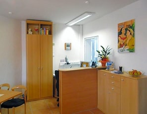 A reception area with a desk, chairs, a wooden cabinet, and a potted plant. - Hotel Deisterblick (Bad Nenndorf)