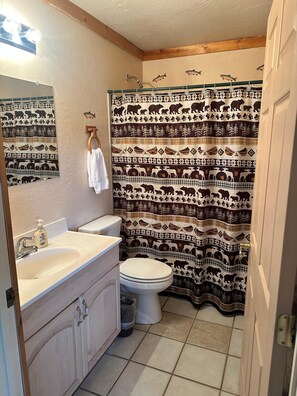 Baño con inodoro, lavamanos y cortina de ducha con estampados de animales.