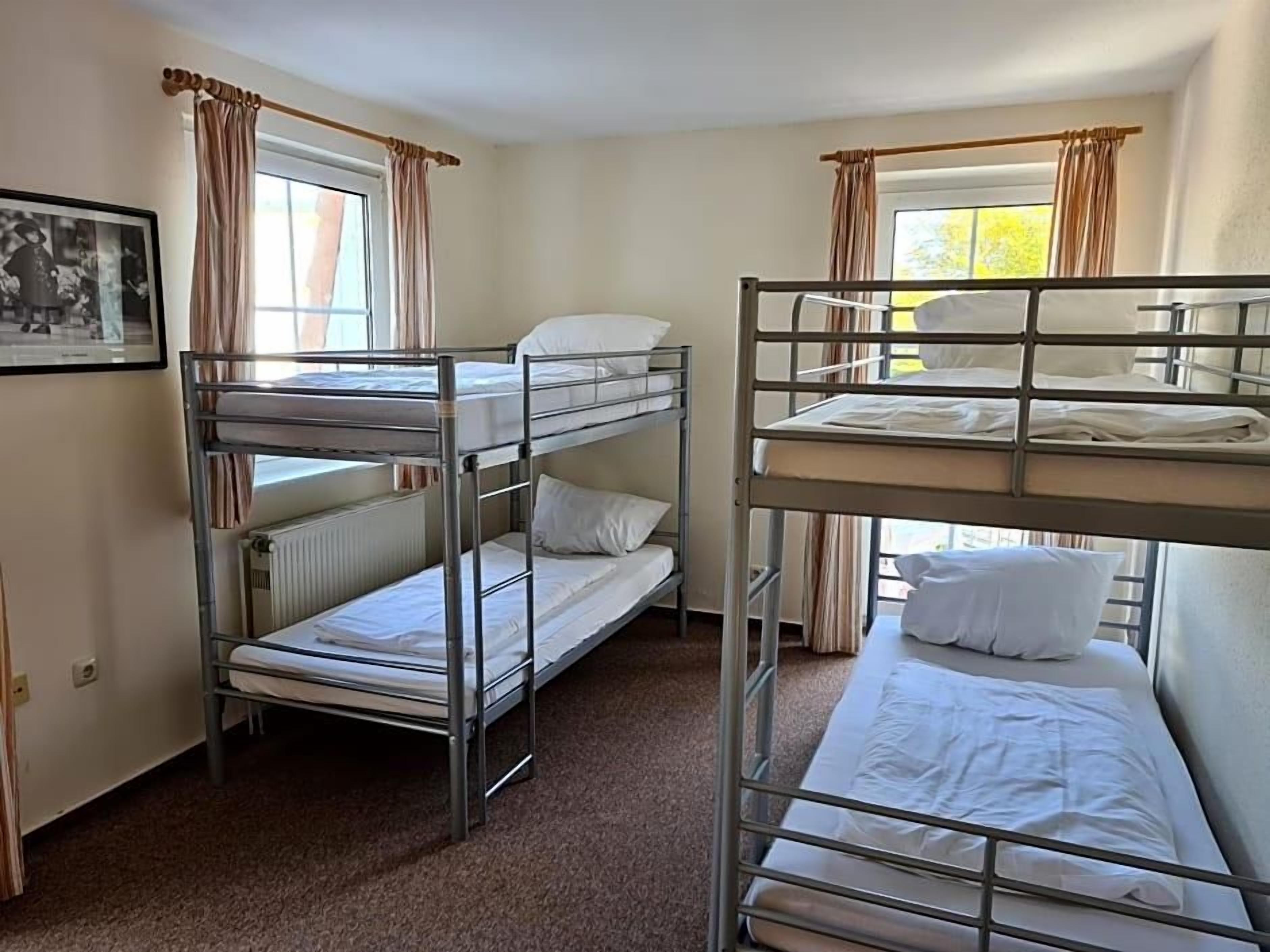 A room with bunk beds, a radiator, and a framed picture on the wall.
