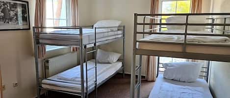 A room with bunk beds, a radiator, and a framed picture on the wall.
