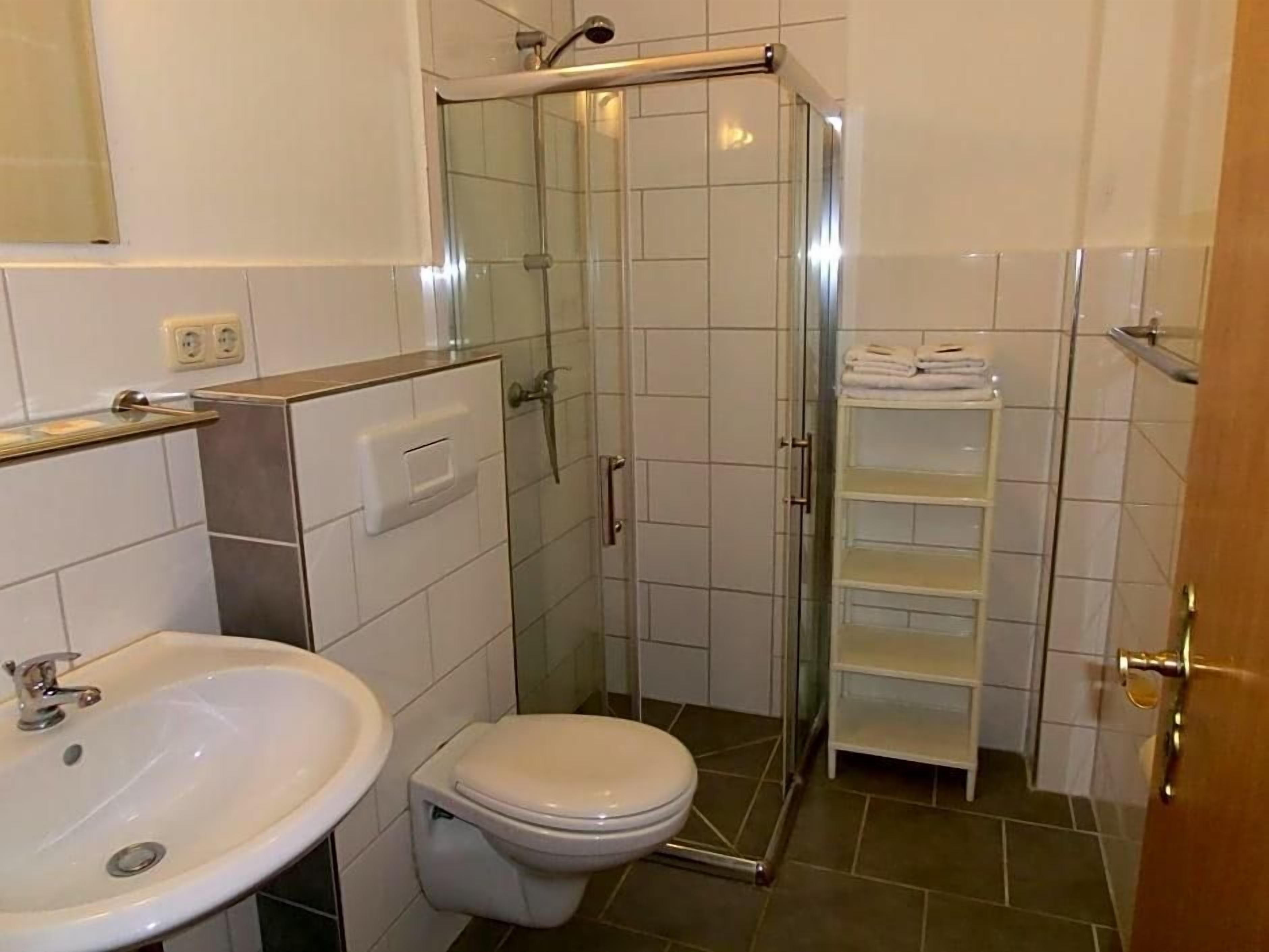 Ein Badezimmer mit einer Duschkabine, einem weißen Waschbecken und einer Toilette.