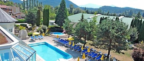 Um resort com piscina, espreguiçadeiras e área envidraçada.