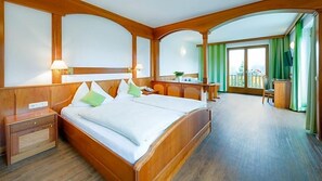 Ein Hotelzimmer mit einem großen Bett, einem Schreibtisch, einem Sessel und einem Balkon mit Vorhängen.