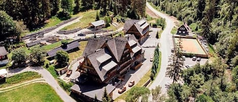 Un chalet comprenant plusieurs bâtiments, un espace de stationnement et une forêt environnante.