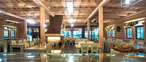 Un espacio interior amplio con vigas de madera en el techo, mesas, sillas y un elemento decorativo central.