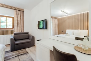 Ein modernes Hotelzimmer mit einer Couch, einem Bett, einem Fernseher und einem großen Spiegel.
